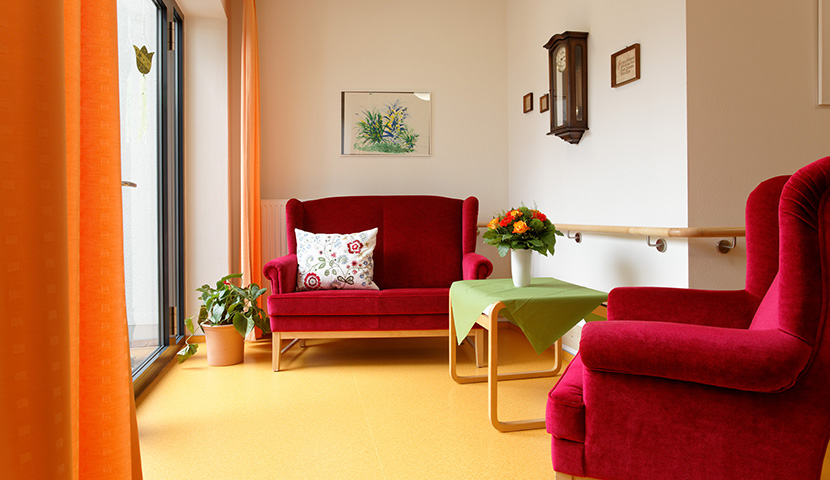 Sitzecke mit zwei roten Sofas und bodentiefen Fenstern