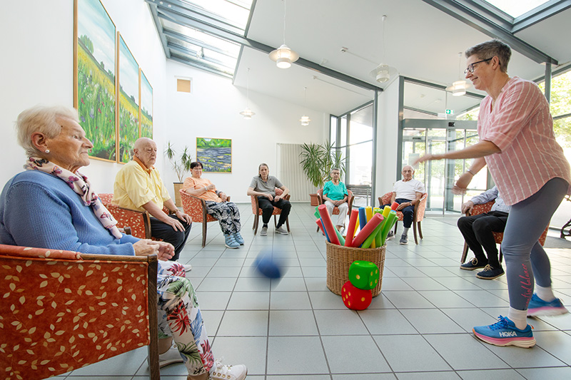 Pflegefachfrau bei Morgengymnastik mit sitzenden Bewohnern