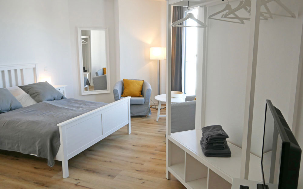 Ein Zimmer mit einem Doppelbett an der linken Wand und einer Garderobe an der rechten Wand