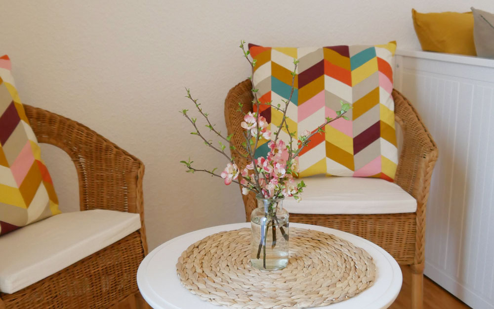 Nahaufnahme von einer Sitzecke mit zwei Korbstühlen und Beistelltisch mit einer Blumenvase darauf