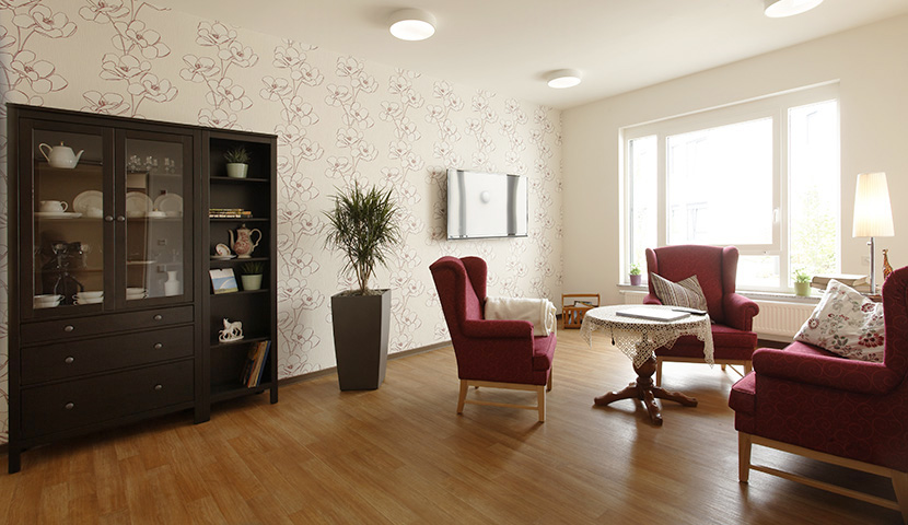 Wohnzimmer mit Schrank, Sesseln und bodentiefen Fenstern