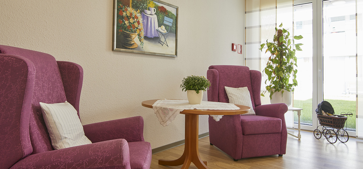 Eine Entspannungsecke mit zwei Sesseln und Blick in den Garten der Tagespflege Augustdorf