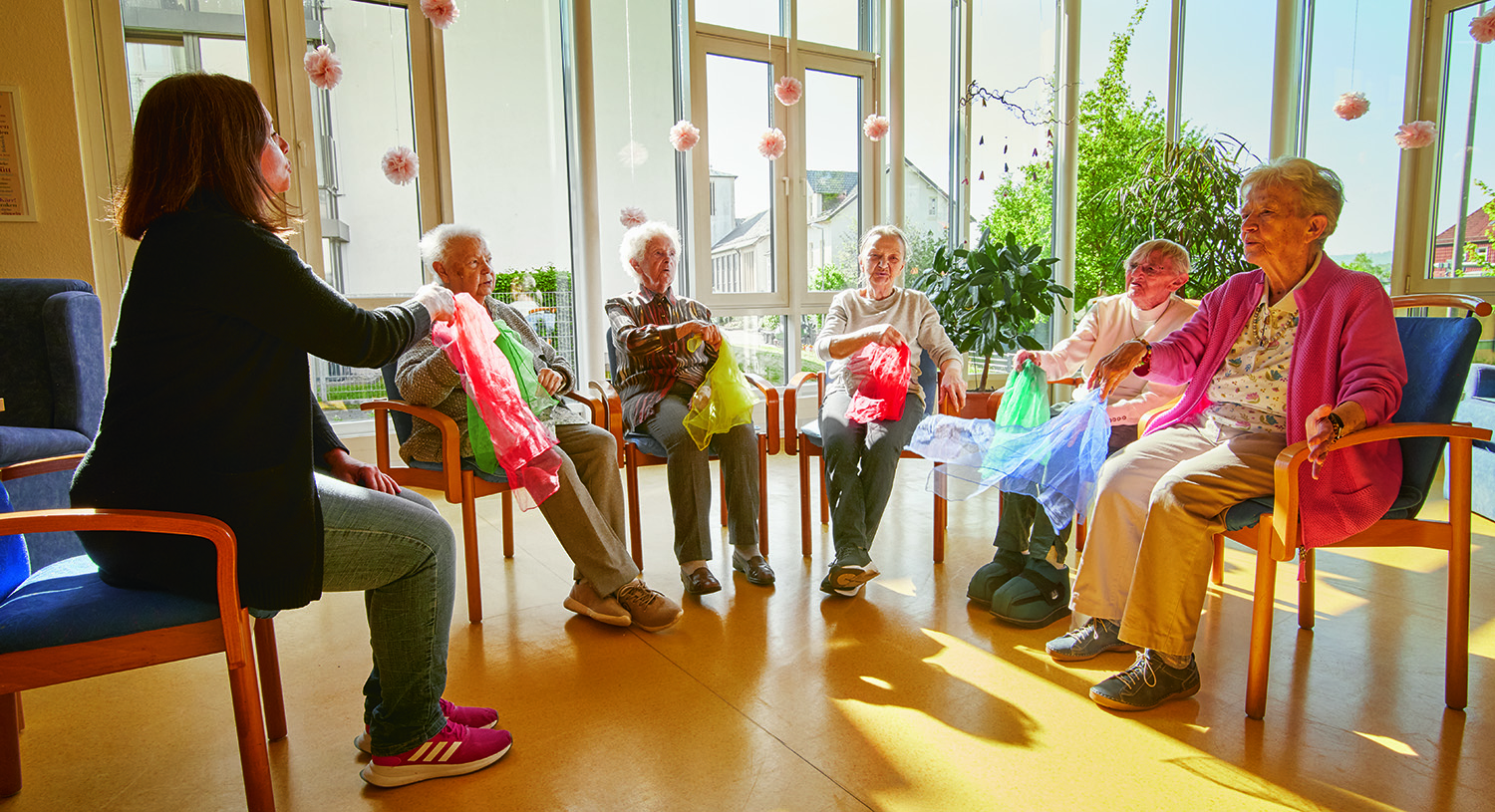 Gruppe macht Übungen im Sitzen mit Tüchern