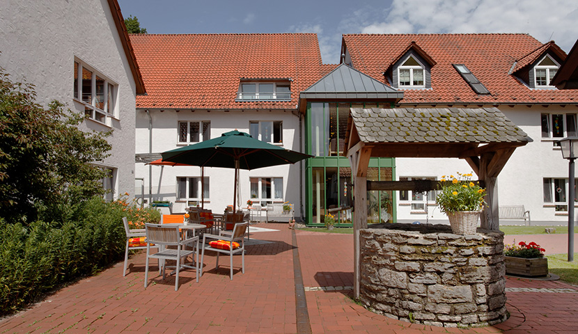 Der Innenhof mit historischem Brunnen, Sitzgarnitur und Sonnenschirm