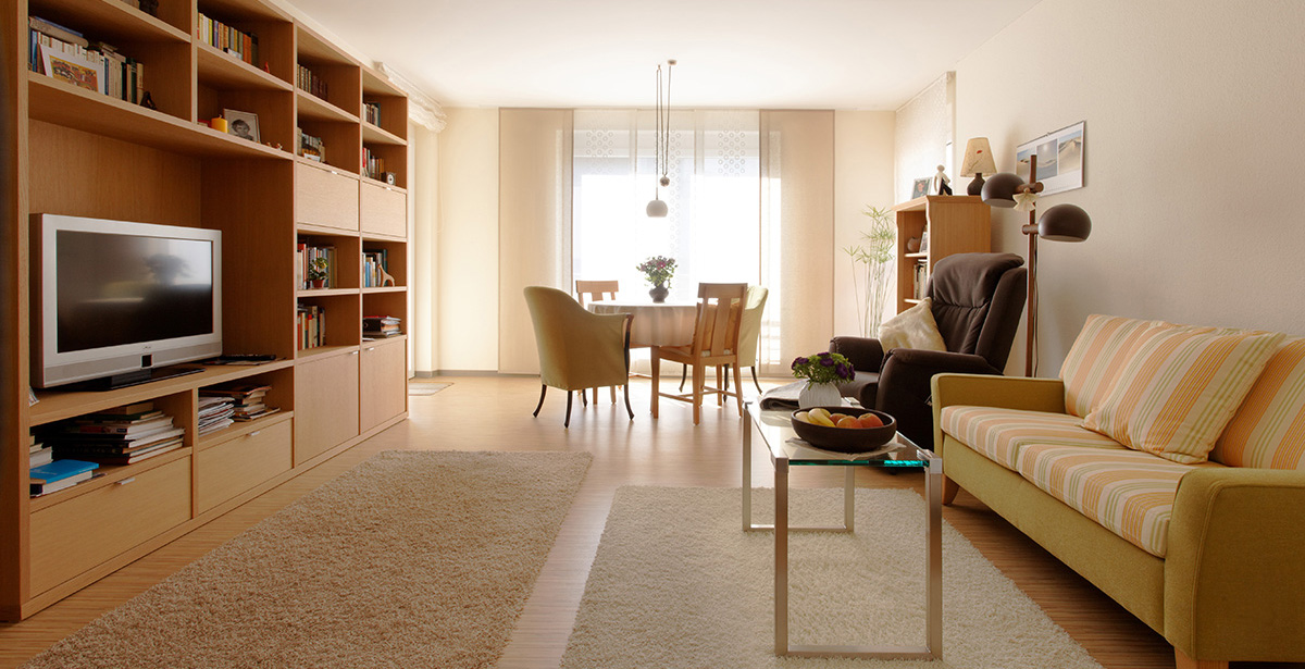Helle Wohnung mit Sofa, Schrankwand und Blick auf die Fenster