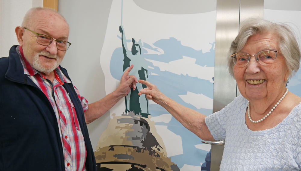 Eine Bewohnerin und ein Bewohner zeigen auf ein Bild mit dem Hermannsdenkmal.