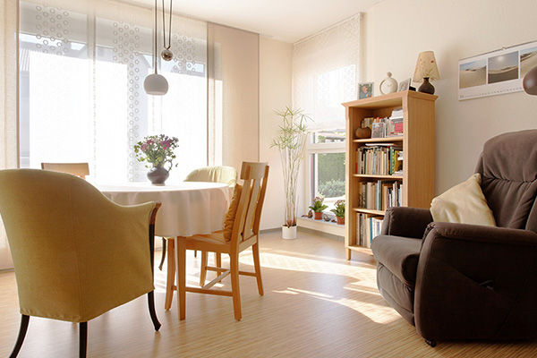 Wohnzimmer mit Sessel, Tischgruppe und Bücherregal